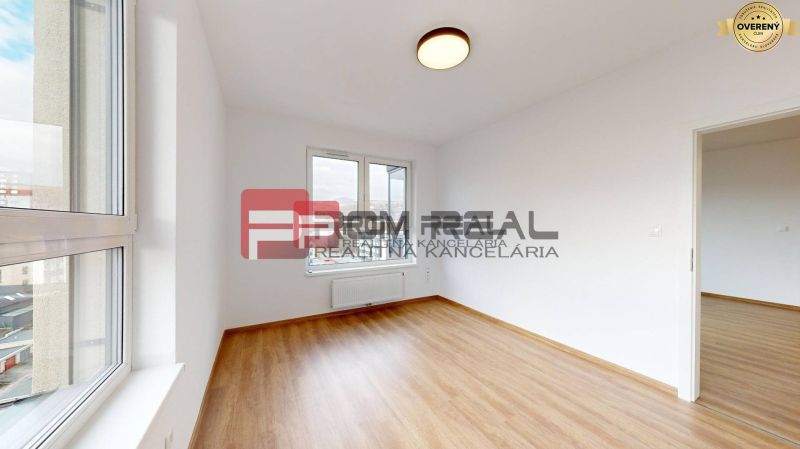 A room in a three-room apartment with a wooden decor floor and a large window.