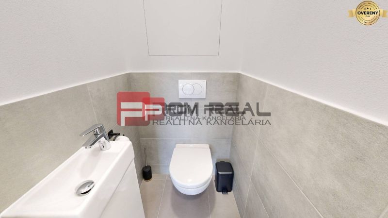 A toilet with a sink and modern tiles in a 3-room apartment.