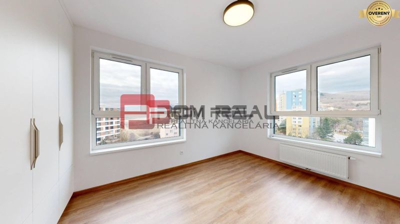 Spacious room with wood-patterned flooring, large windows, and a built-in wardrobe.