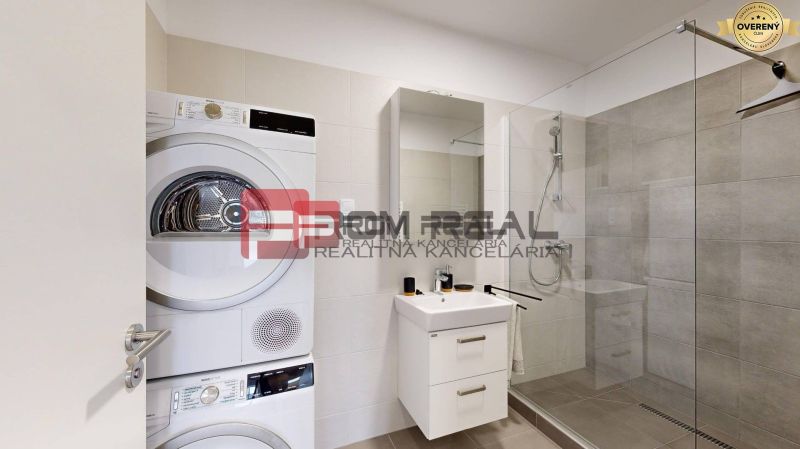 Bathroom of a 3-room apartment with a washing machine, dryer, and shower.