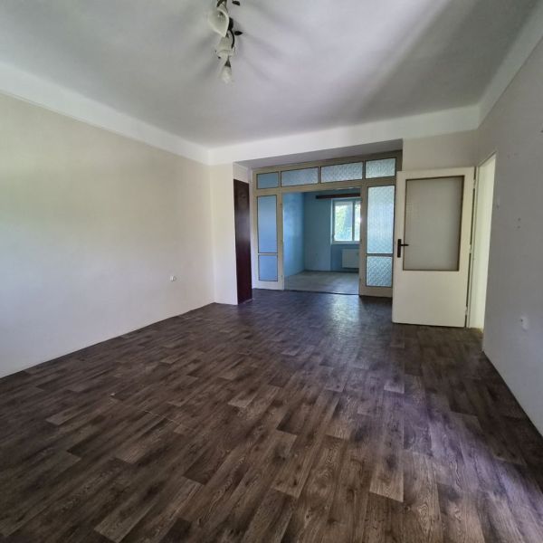 A room in a 3-room apartment with a floor featuring a wooden decor and white walls.