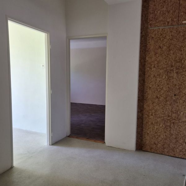 A simple hallway in a 3-room apartment with a wooden decor floor.