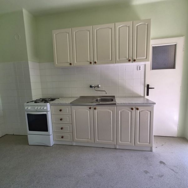 A kitchen in a 3-room apartment with a gas stove and white cabinets.