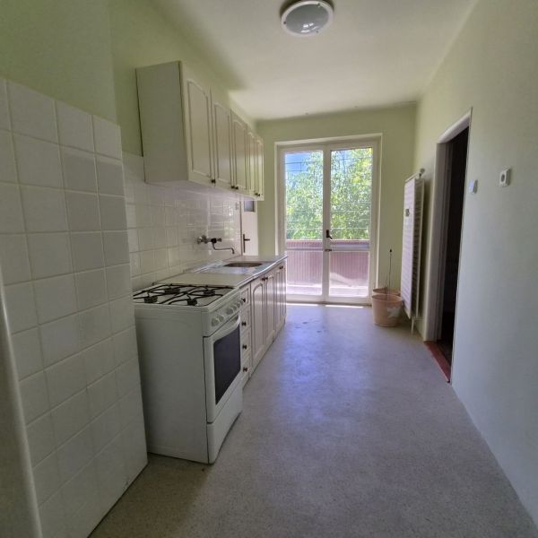 A kitchen in a 3-room apartment with a stove and a view of the balcony.