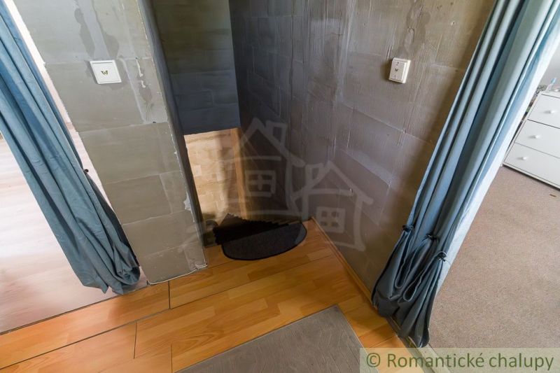 The interior of a cabin with stairs and a wooden decor floor, complemented by curtains.