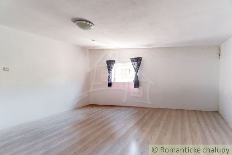 A room with a wall, a window, and a wooden decor floor in a cabin.