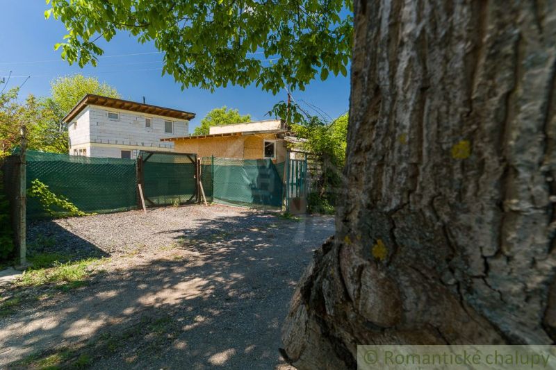 A cottage in Bernolákovo surrounded by greenery and a fenced yard.