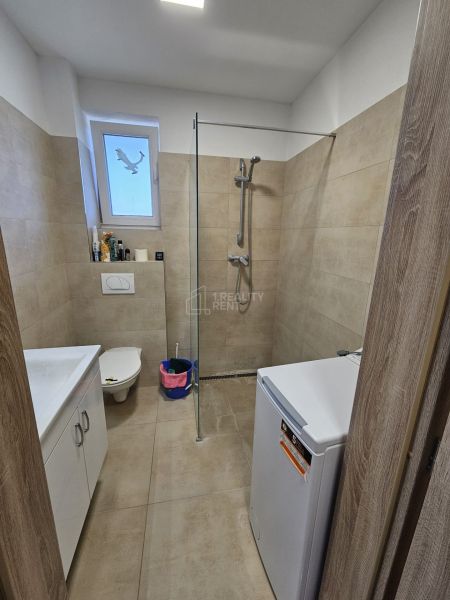 A bathroom in a studio apartment with a barrier-free shower and modern tiles.