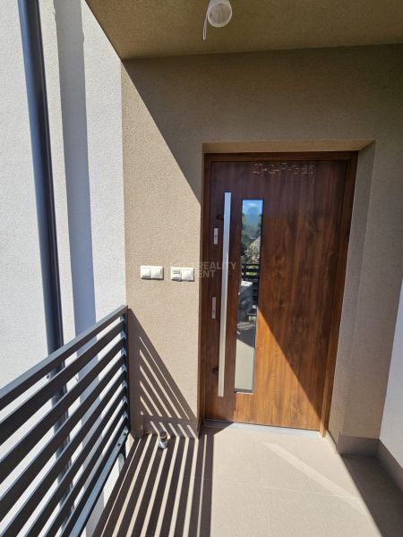 Entrance door to a one-room apartment with a wood decor and a balcony railing.