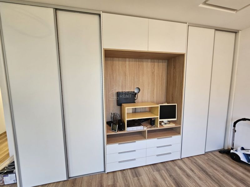 Built-in wardrobe with a work nook, floor with wooden decor in a studio apartment.