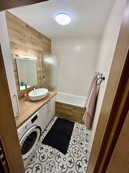 Bathroom in a 3-room apartment with a washing machine and a wooden decor floor.