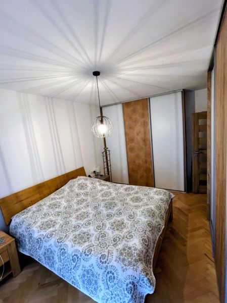 Bedroom with wood-patterned flooring and a large bed in a 3-room apartment.