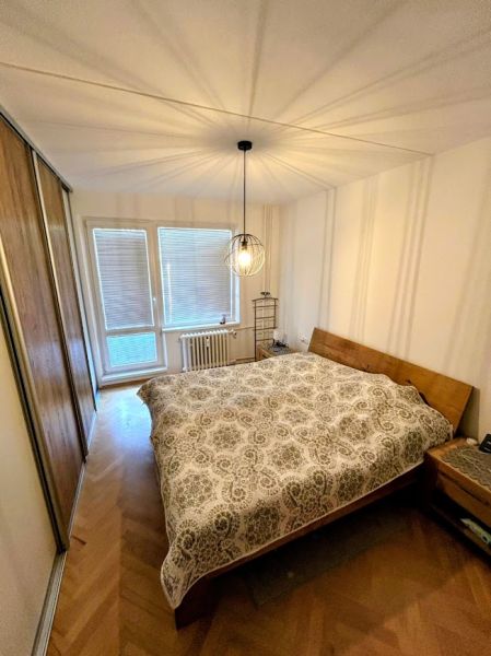 Bedroom in a 3-room apartment with a wood-patterned floor and practical lighting.