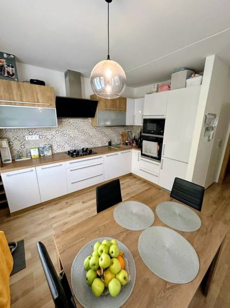 A kitchen in a 3-room apartment with white cabinets and a wood-patterned floor.