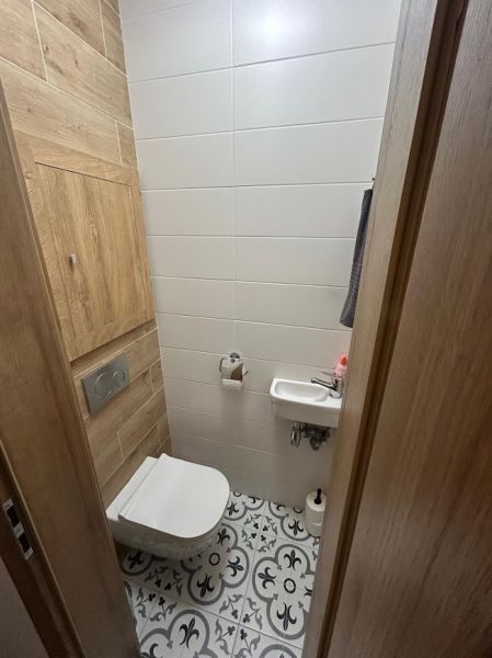 Toilet arrangement with wood decor flooring and decorative tiles in a 3-room apartment.