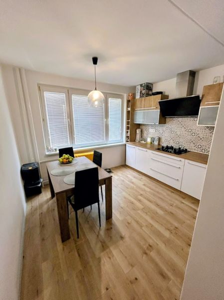 A kitchen in a 3-room apartment with a wooden decor floor and a dining table.