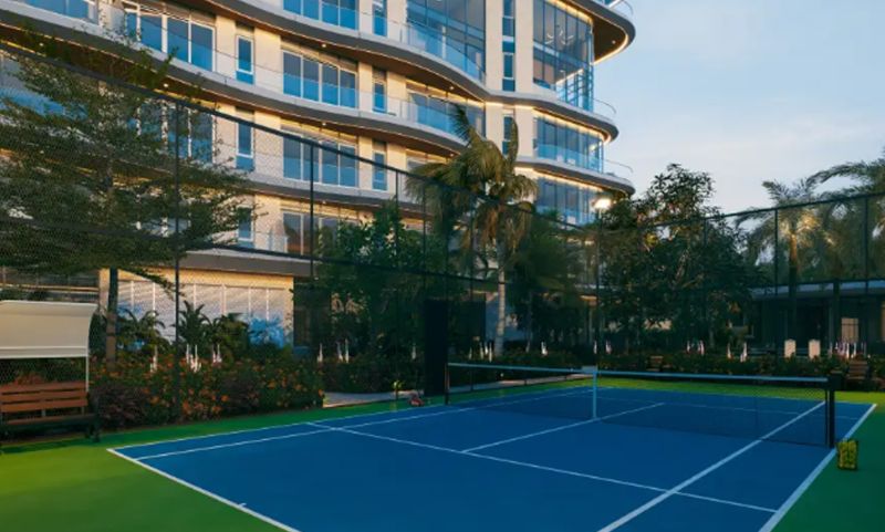 A tennis court in front of a modern building in Paje surrounded by greenery and palm trees.