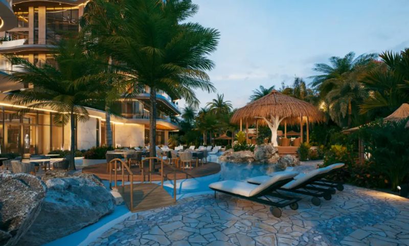 An evening view of a tropical resort with a pool in Paje surrounded by palm trees.
