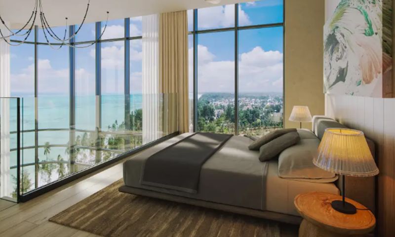 A glazed bedroom in a studio apartment with an ocean view and wood-patterned flooring.