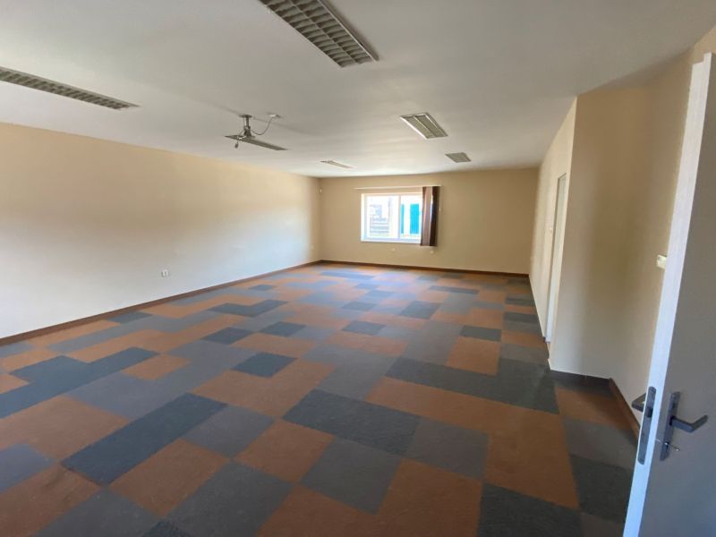 Commercial space with a geometric floor and a window, ideal for rent or an office.
