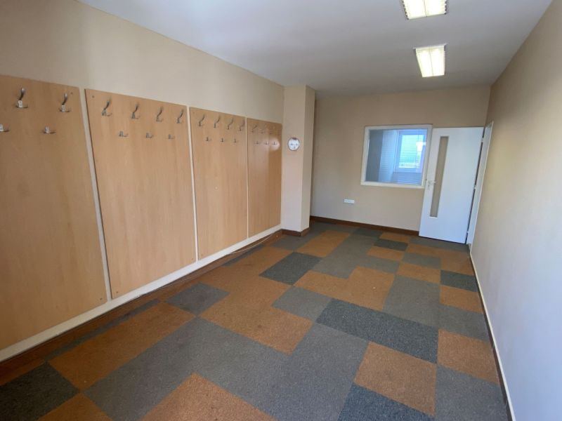 Commercial space with patterned flooring, wall hooks, and white doors.
