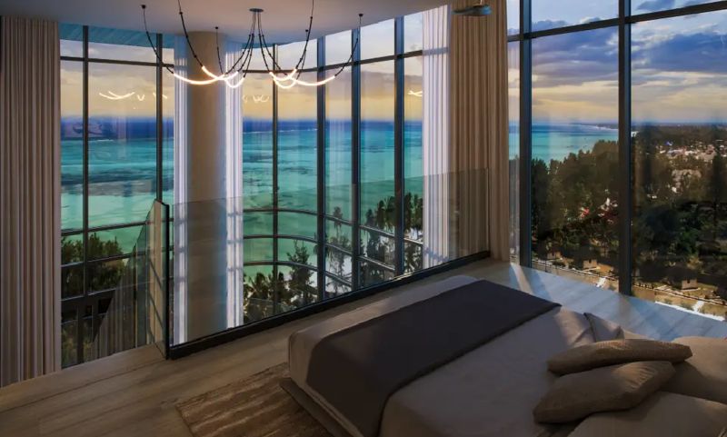 A bedroom in a studio apartment with large windows and an ocean view.