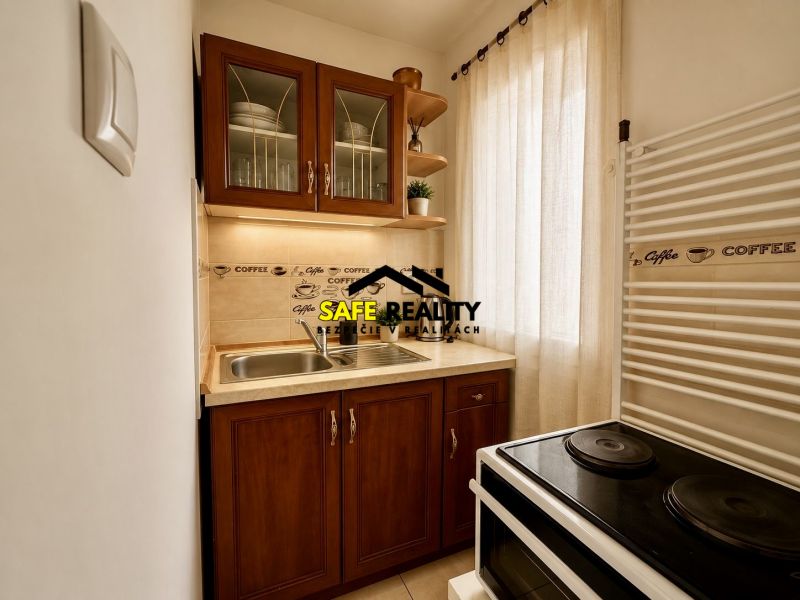 A kitchenette in a studio apartment with two cabinets, a curtain, and an electric stove.