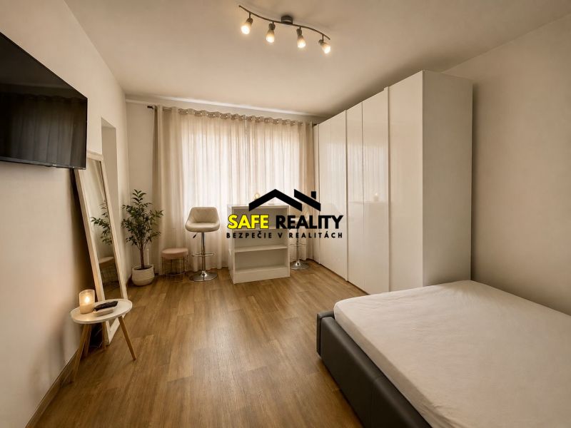 Studio apartment with wood-patterned flooring, a large mirror, a bed, and a wardrobe.