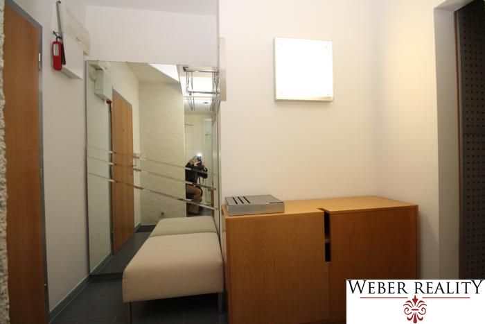 A hallway in a 3-room apartment with a mirror, a bench, and a wooden cabinet.