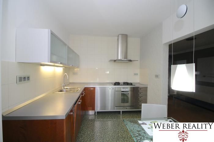 A kitchen in a 3-room apartment with metal appliances and stylish lighting.