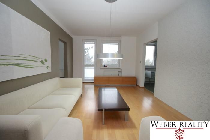 Living room in a three-room apartment with a wooden decor floor and a comfortable sofa.