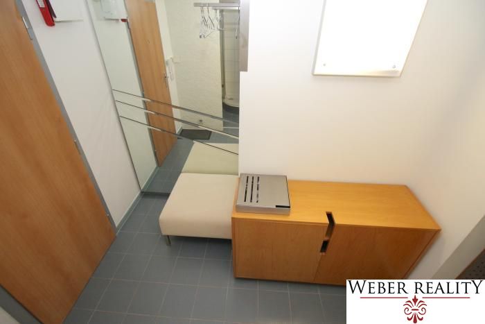 Entrance hallway of a 3-room apartment with a coat rack, bench, and cabinet on tiles.