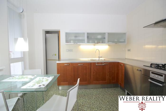 A kitchen in a 3-room apartment with a dining table and white chairs.