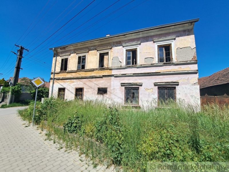 A family house in Klátova Nová Ves with a cracked facade and an overgrown garden.