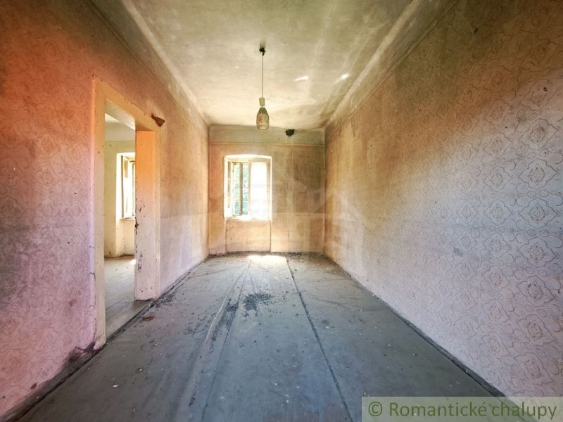 An older room in a family house with worn-out wallpaper and a simple light fixture.