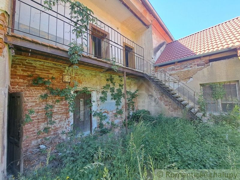 A family house in Klátova Nová Ves with a brick facade, covered in greenery, and a staircase.