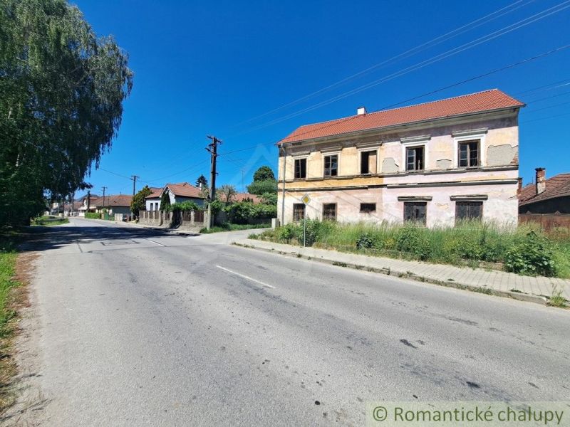 A street with a historic family house in Klátova Nová Ves under a blue sky.