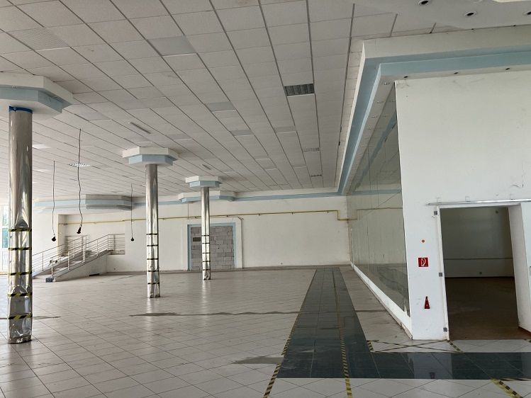 Commercial spaces with white tiles, columns, and stairs in the background.