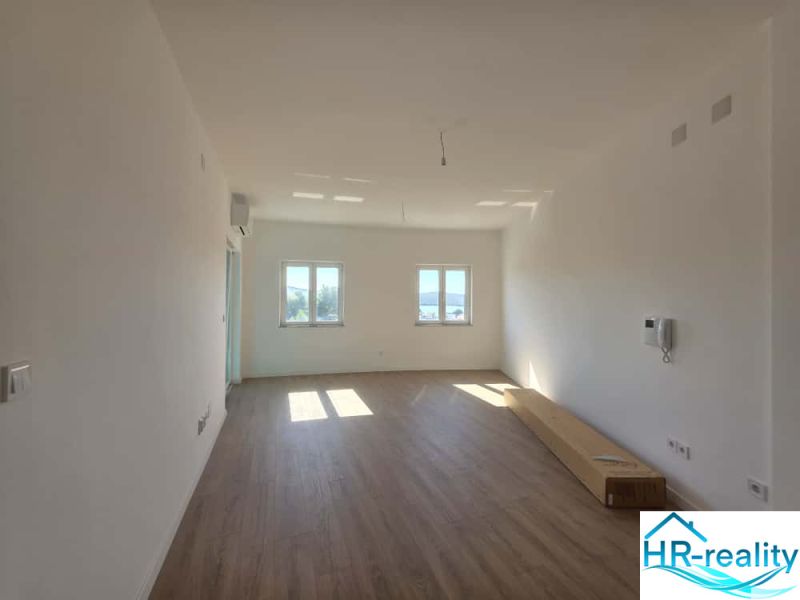 A bright room in a 2-room apartment with a wooden decor floor and a view of the window.