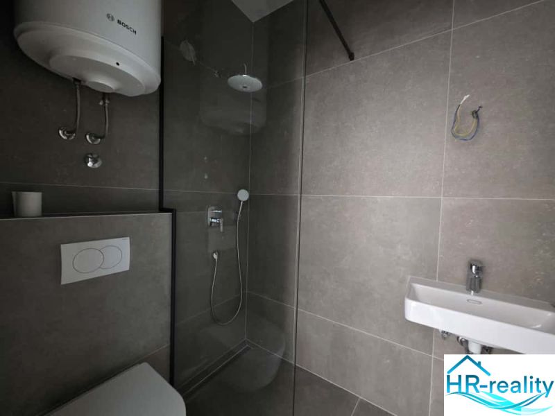The bathroom in the 2-room apartment has a shower, a toilet, and a sink.