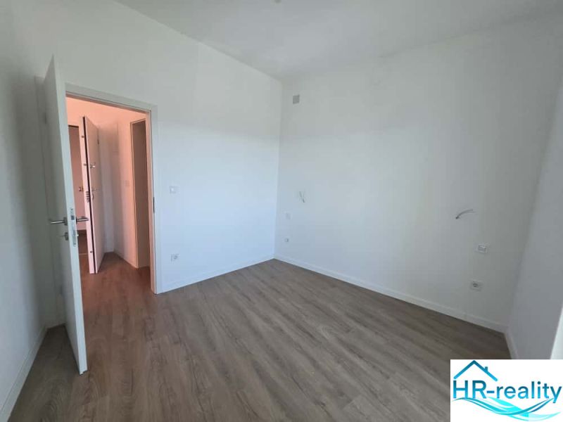 A room with white walls and a wooden decor floor in a 2-room apartment.