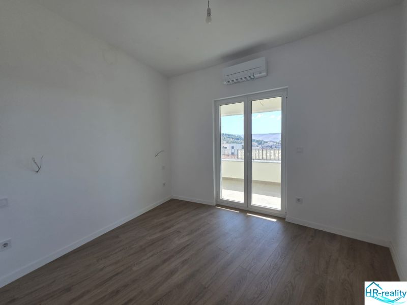 A room in a two-room apartment with a wooden decor floor and a balcony.