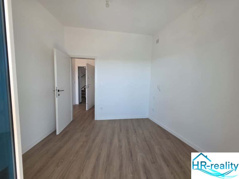 Interior of a 2-room apartment with wood-patterned flooring and white walls.