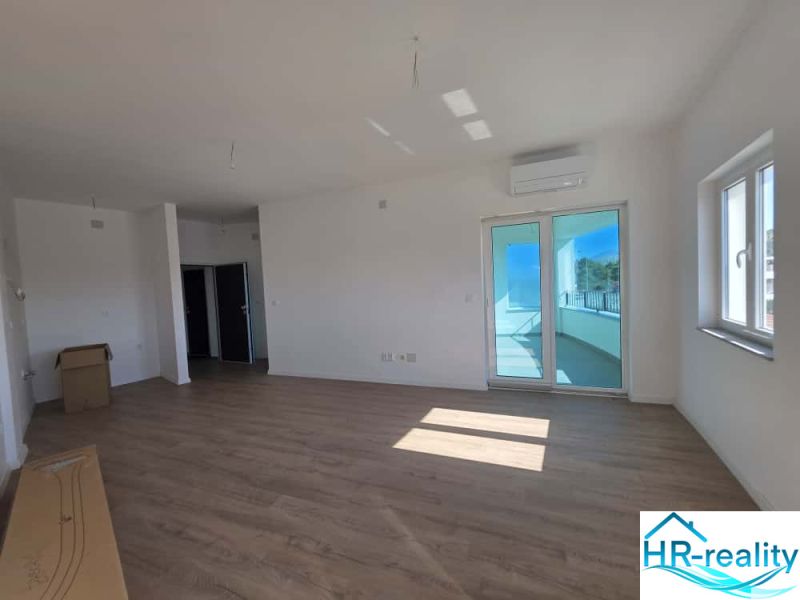 Living room of a two-room apartment with a wooden decor floor and balcony doors.