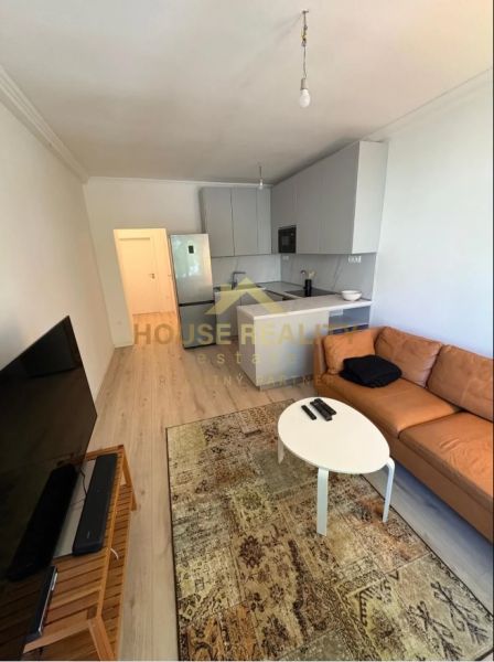 Living room with a sofa, TV, carpet, and kitchen in a 3-room apartment.