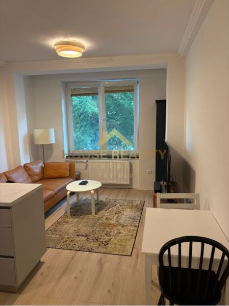 Living room in a 3-room apartment with a leather sofa and a wooden decor floor.