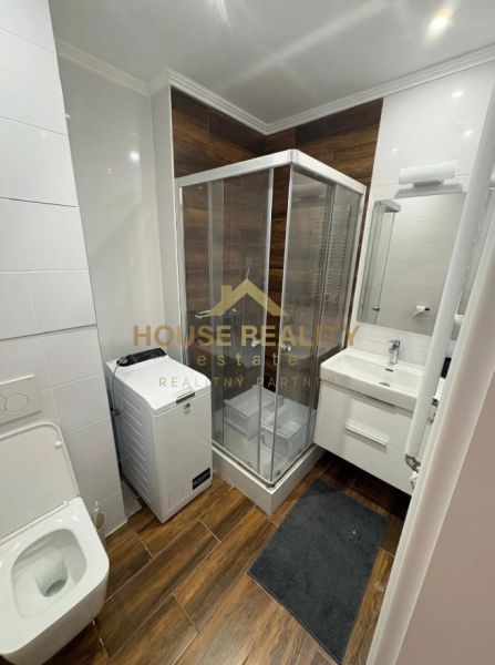 Bathroom with toilet, shower, washing machine, and wooden decor flooring in a 3-room apartment.