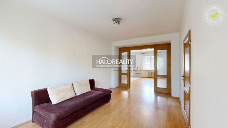 Living room in a three-room apartment with a wooden decor floor and a sofa.