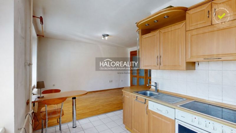 A kitchen in a three-room apartment with a wooden decor floor and light furniture.
