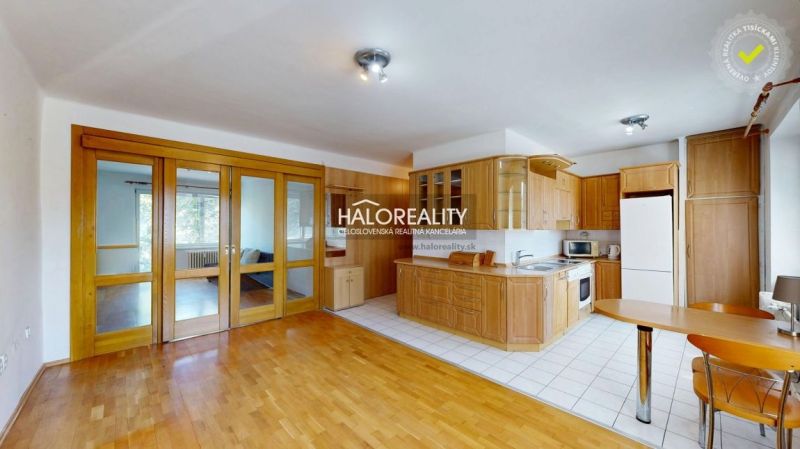 Kitchen connected with living room, wooden decor flooring, 3-room apartment.